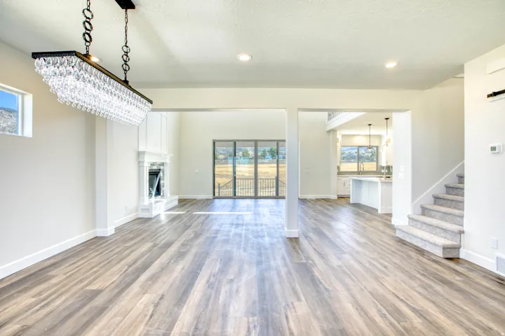 Spacious interior with wood-finish flooring, a white mantel fireplace, and a crystal chandelier