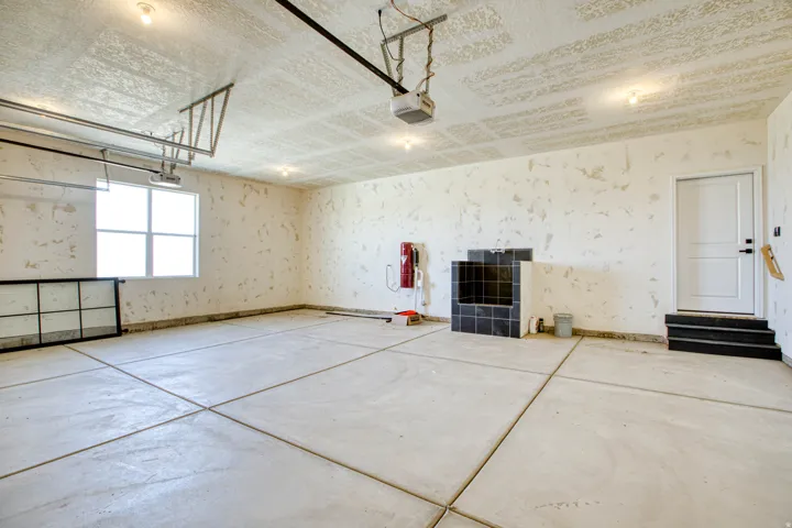 Spacious garage featuring a window, built-in black tiled utility sink, concrete flooring, and a service door