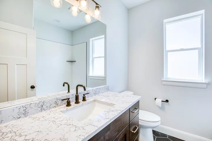 Vanity with a white countertop and integrated sink, bronze-finish faucet, and coordinating hardware