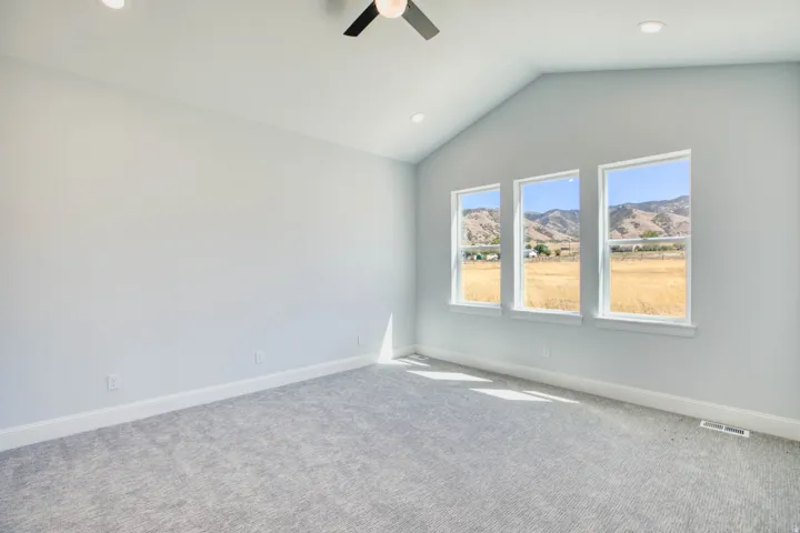 Vaulted ceiling with recessed lighting and ceiling fan, three pane windows, plush carpet flooring, and mountain scenery