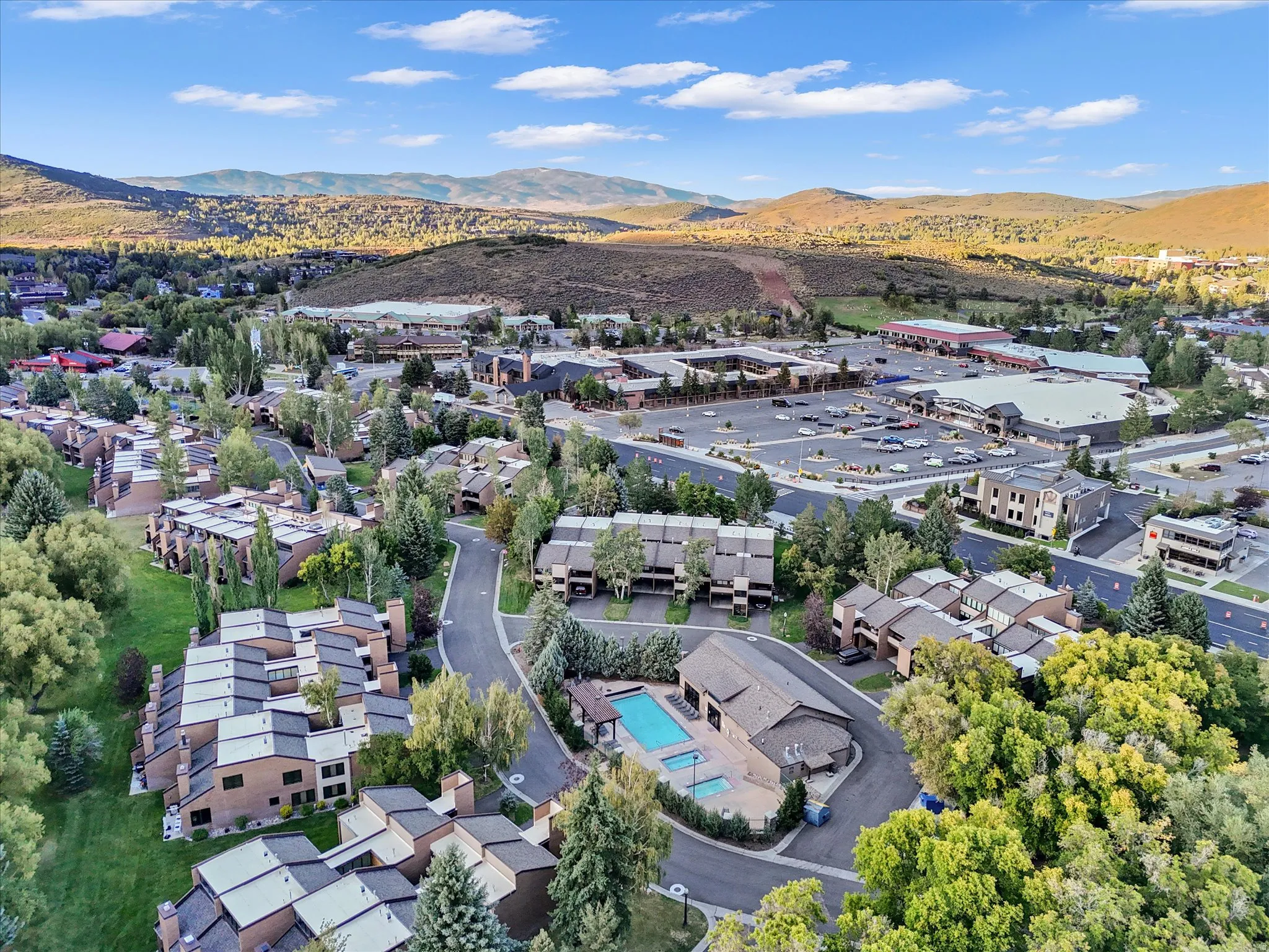 Overhead view of clubhouse, pool, and hot tubs with shopping across street
