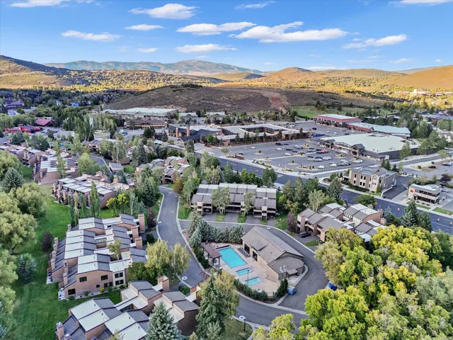 Overhead view of clubhouse, pool, and hot tubs with shopping across street