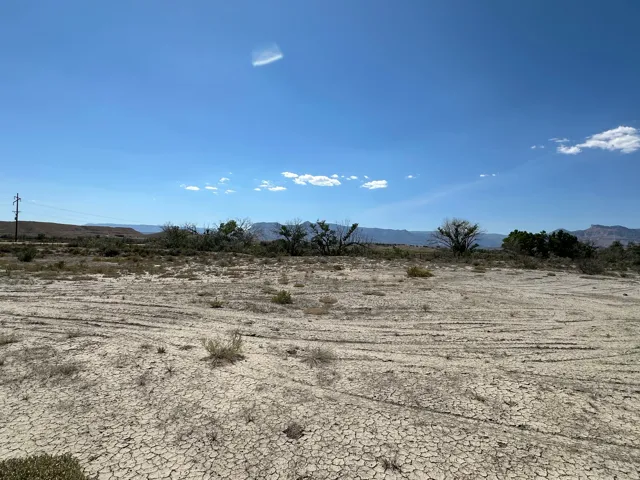 Expansive arid terrain with distant mountain formations and natural vegetation