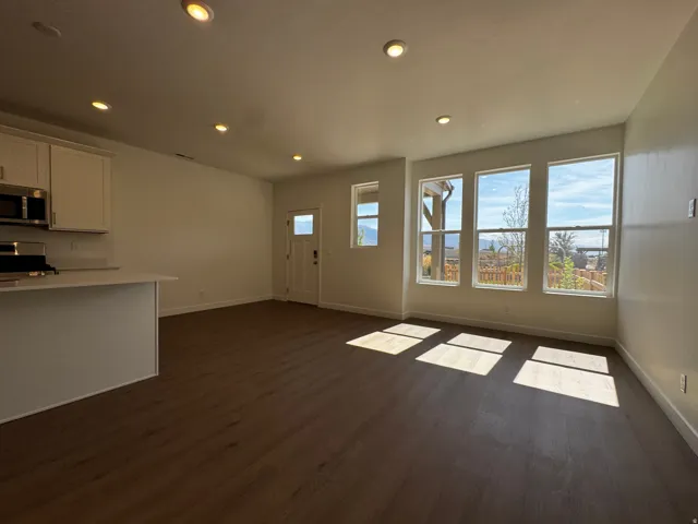 Recessed lighting, wood-finish flooring, white cabinetry, stainless steel appliances, and multiple windows