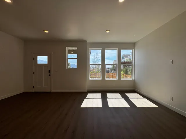 Wood-finish flooring throughout, recessed ceiling lighting, multiple windows, and a panel door with a window lite