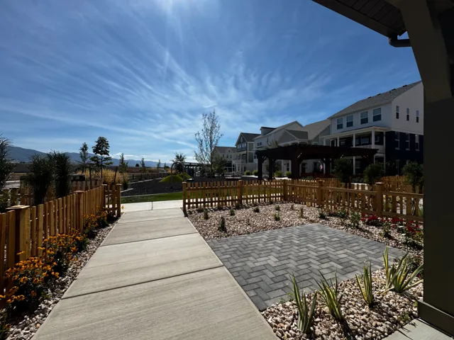 Private paver patio, wood picket fencing, concrete pathway, and landscaped garden beds