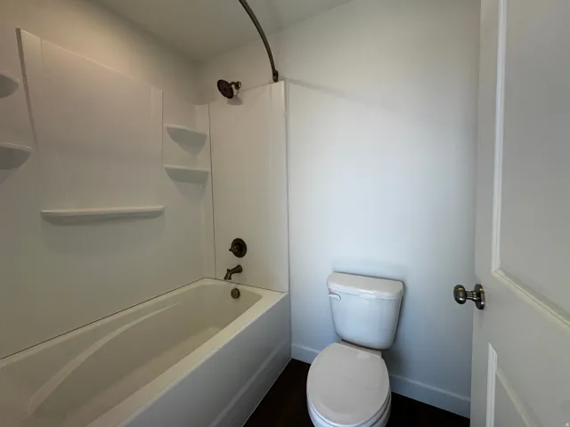 White three-piece bathroom suite featuring a shower/tub combination with integrated shelving