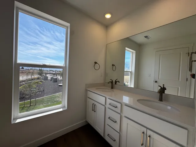 Dual vanity with white cabinetry, light-toned countertops, and bronze-finish fixtures