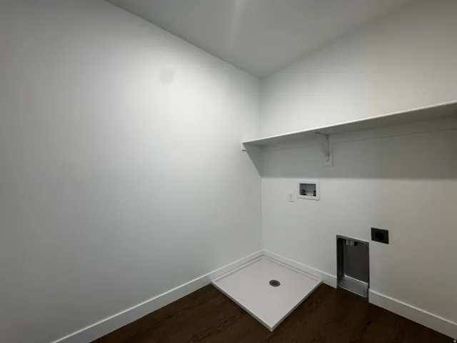 Laundry area featuring a utility sink, white wall shelving, and wood-finish flooring