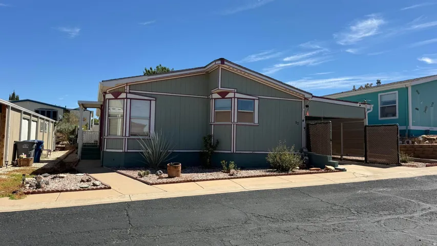 Exterior featuring light green siding, bay windows, and a covered carport