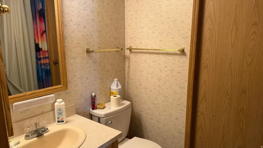 Bathroom featuring a vanity with an integrated sink, a framed mirror, and a toilet
