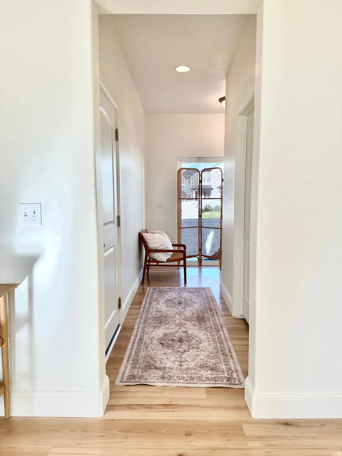 Recessed lighting illuminating a hallway with wood-finish flooring and white paneled interior doors