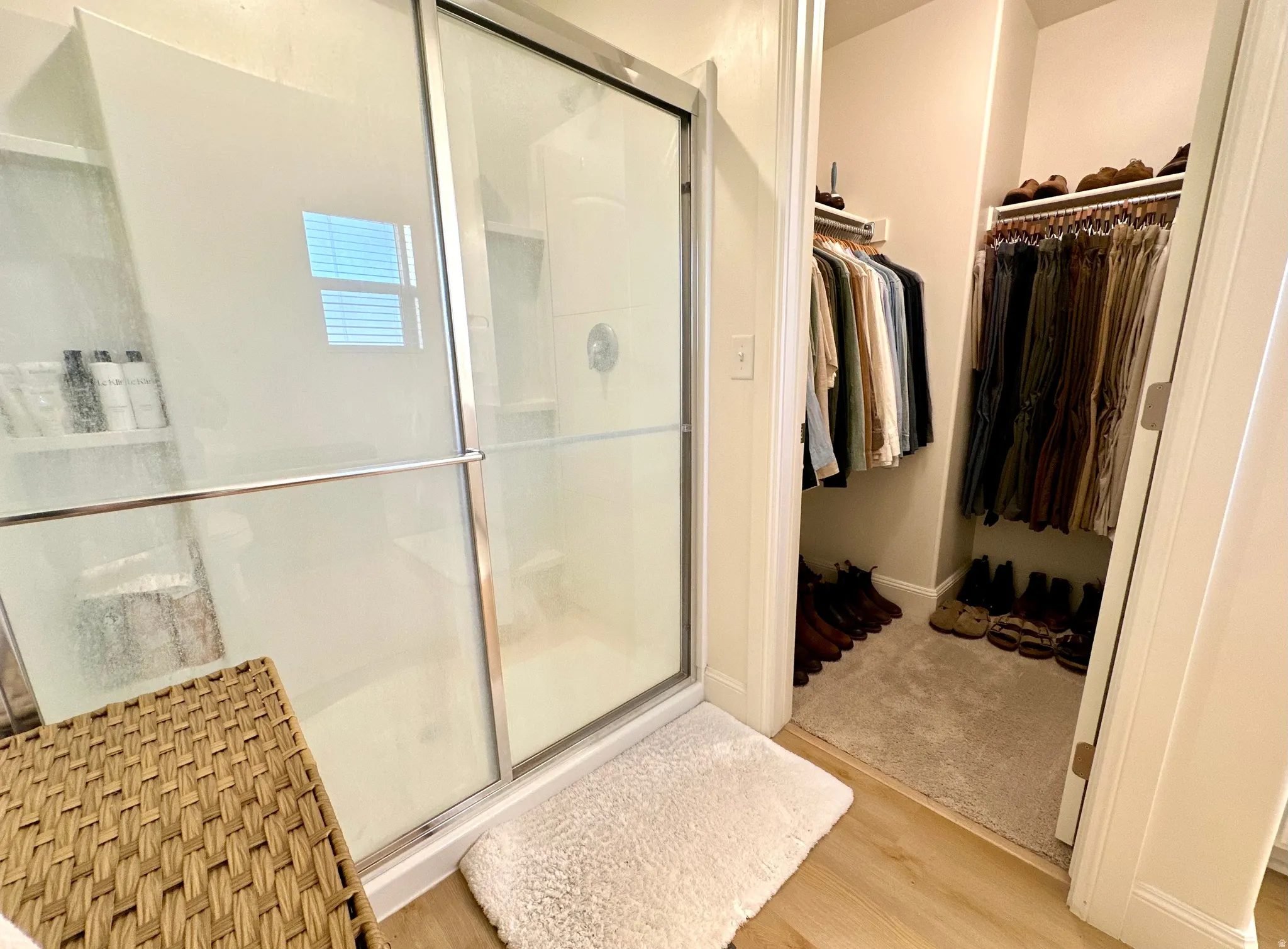 Glass-enclosed shower with sliding door and chrome hardware