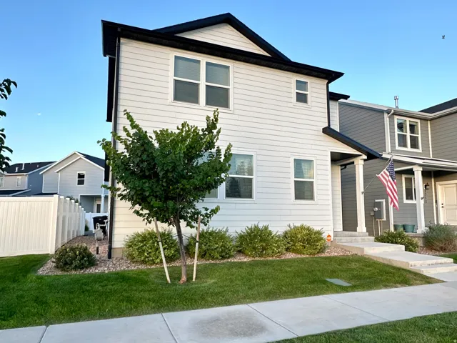Two-story residence with light-colored siding, dark-trimmed windows, and a dark roof