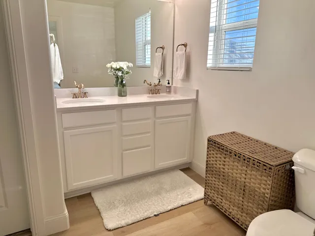 Double vanity with white cabinetry, integrated sinks, and polished brass fixtures