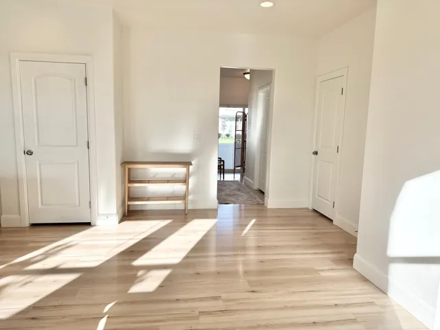 Light wood-finish flooring complemented by white walls, recessed ceiling lighting, and two paneled interior doors