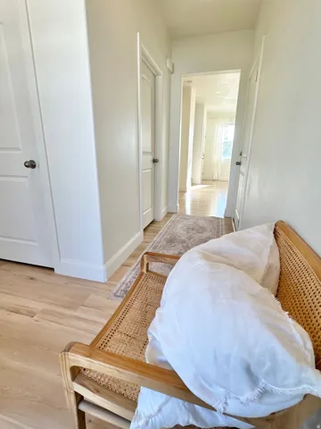Light wood-finish flooring extends through the hallway, complemented by white interior doors with dark hardware