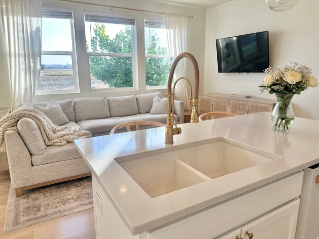 Kitchen island with a double basin sink, brass-finish faucet, and light-toned countertop