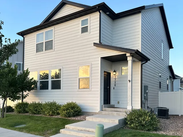 Two-story siding exterior with dark trim accents, covered entry, front concrete walkway, and concrete steps