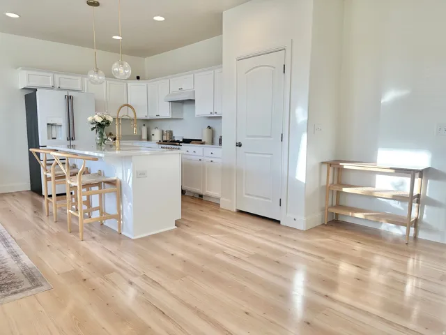 Open-concept kitchen featuring white cabinetry, a central island with countertop seating, and light wood-finish flooring throughout