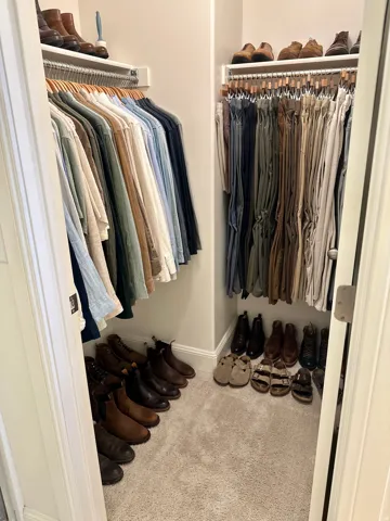 Built-in closet system with upper shelving, hanging rods, and neutral carpet