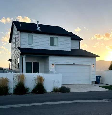 Two-story residence featuring light-colored siding and a dark roof