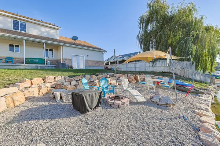 Waterfront property featuring a stone retaining wall, gravel patio, built-in fire pit, and plenty of space for all your gatherings.