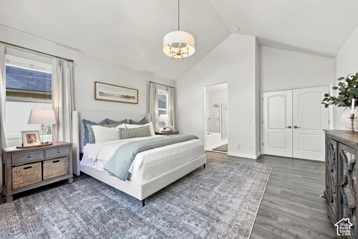 Vaulted ceiling with a contemporary chandelier, wood-finish flooring, double doors, and an en-suite bathroom with a soaking tub and glass shower