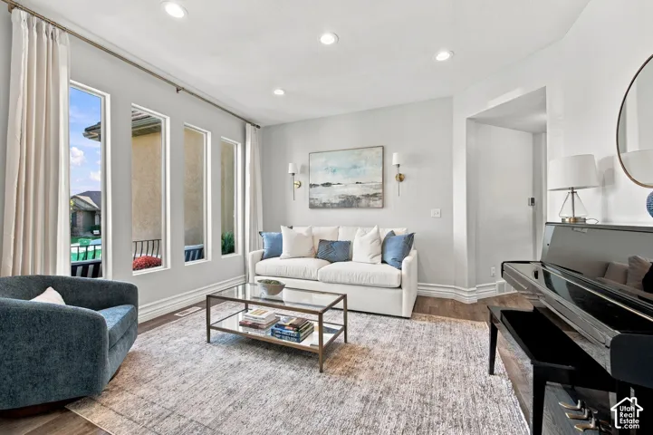 Recessed lighting illuminates the living space with wood-finish flooring