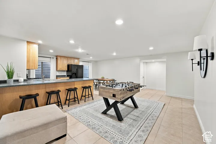 Kitchenette with wood cabinetry and dark countertops, recessed lighting, and tile flooring