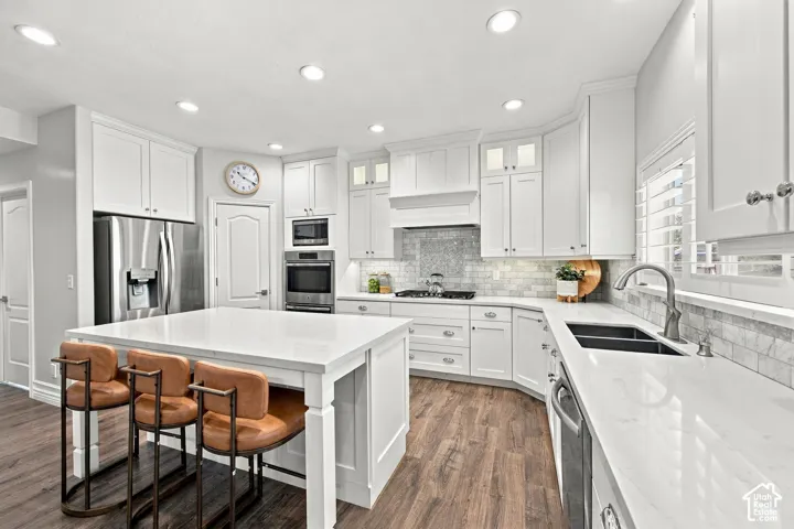Kitchen featuring white cabinetry, stainless steel appliances, wood-finish flooring, a kitchen island, and recessed lighting