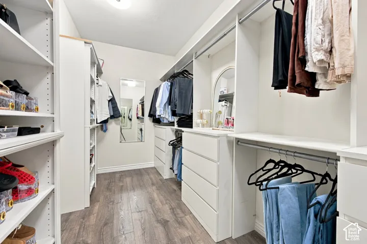 Custom closet system with extensive shelving, multiple hanging rods, built-in drawers, and wood-finish flooring