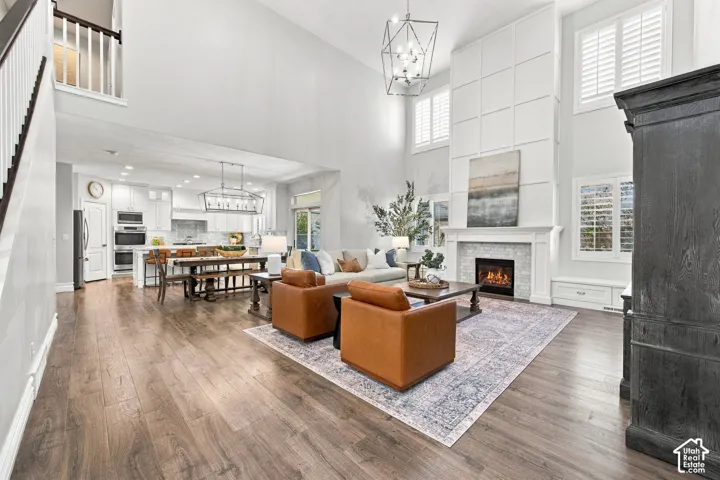 Vaulted ceilings, wood-finish flooring, fireplace with tile surround, white cabinetry, and a double oven
