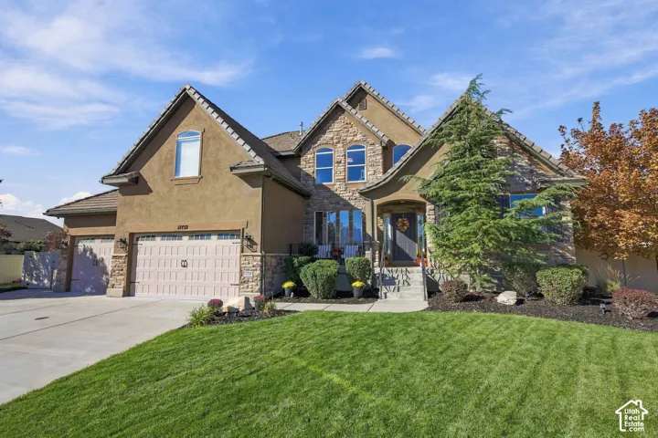 Stucco and stone exterior with arched windows, a covered front entry, a two-car garage, and a concrete driveway