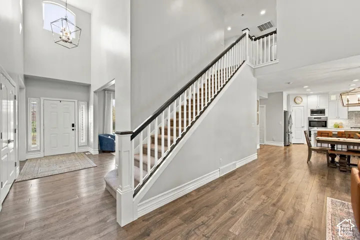 Two-story entryway featuring a decorative light fixture, arched window, and wood-finish flooring