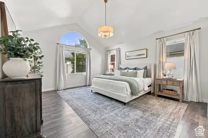 Vaulted ceiling with an arched window, wood-finish flooring, and a drum pendant light fixture