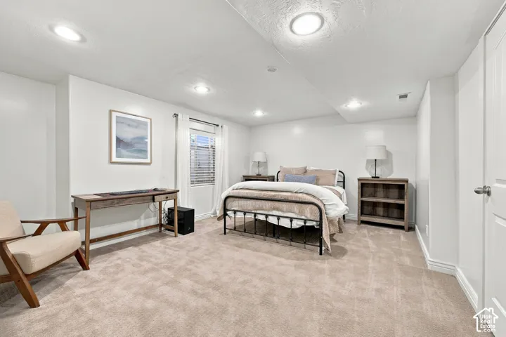 Recessed lighting illuminating the neutral-toned carpet and white walls, complemented by a window with blinds