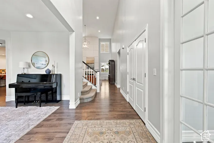 High ceilings with recessed lighting, wood-finish flooring, white paneled doors, and a staircase with white balusters