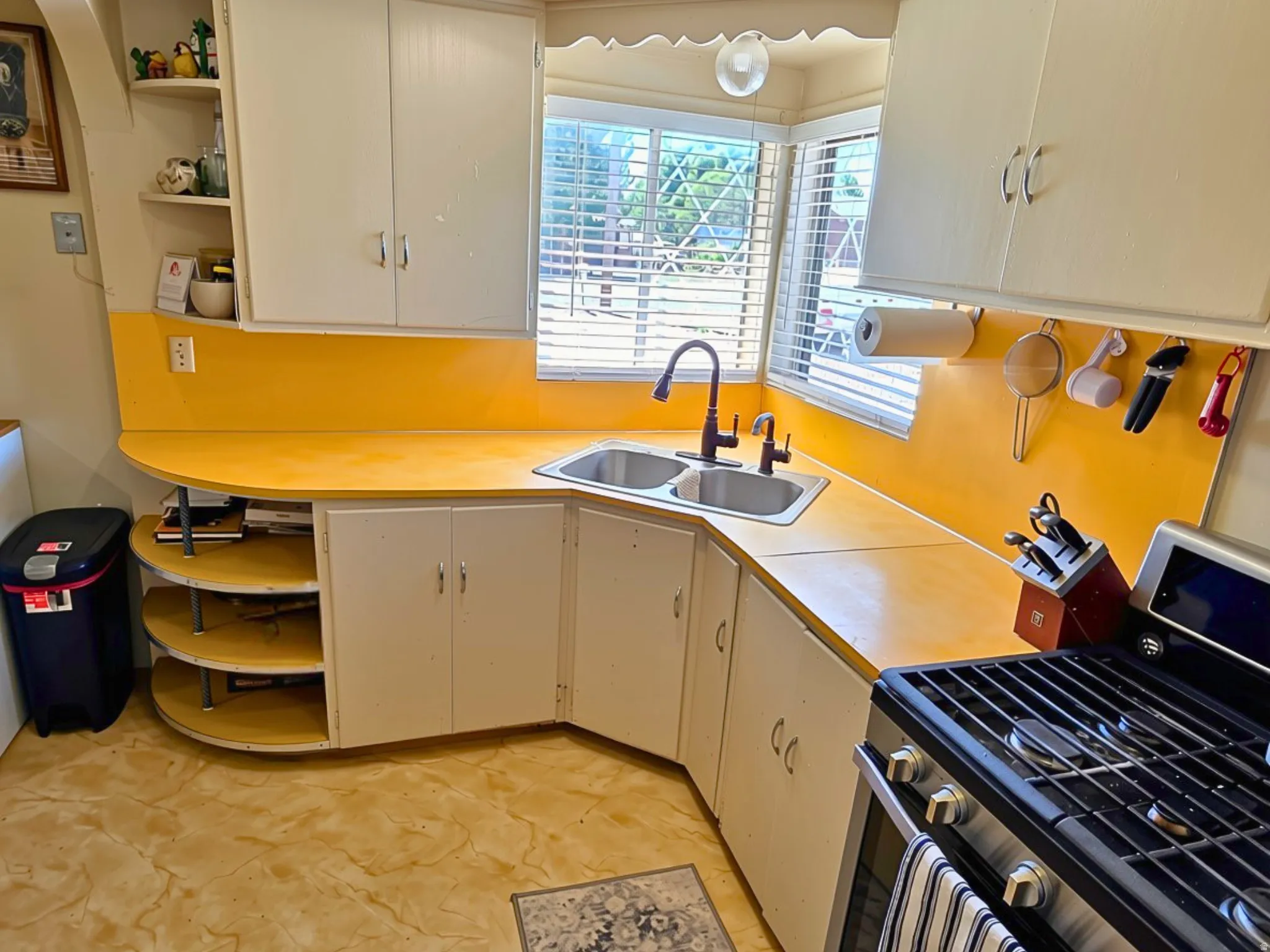 Corner kitchen sink with dual basins and a gooseneck faucet, set into a yellow countertop