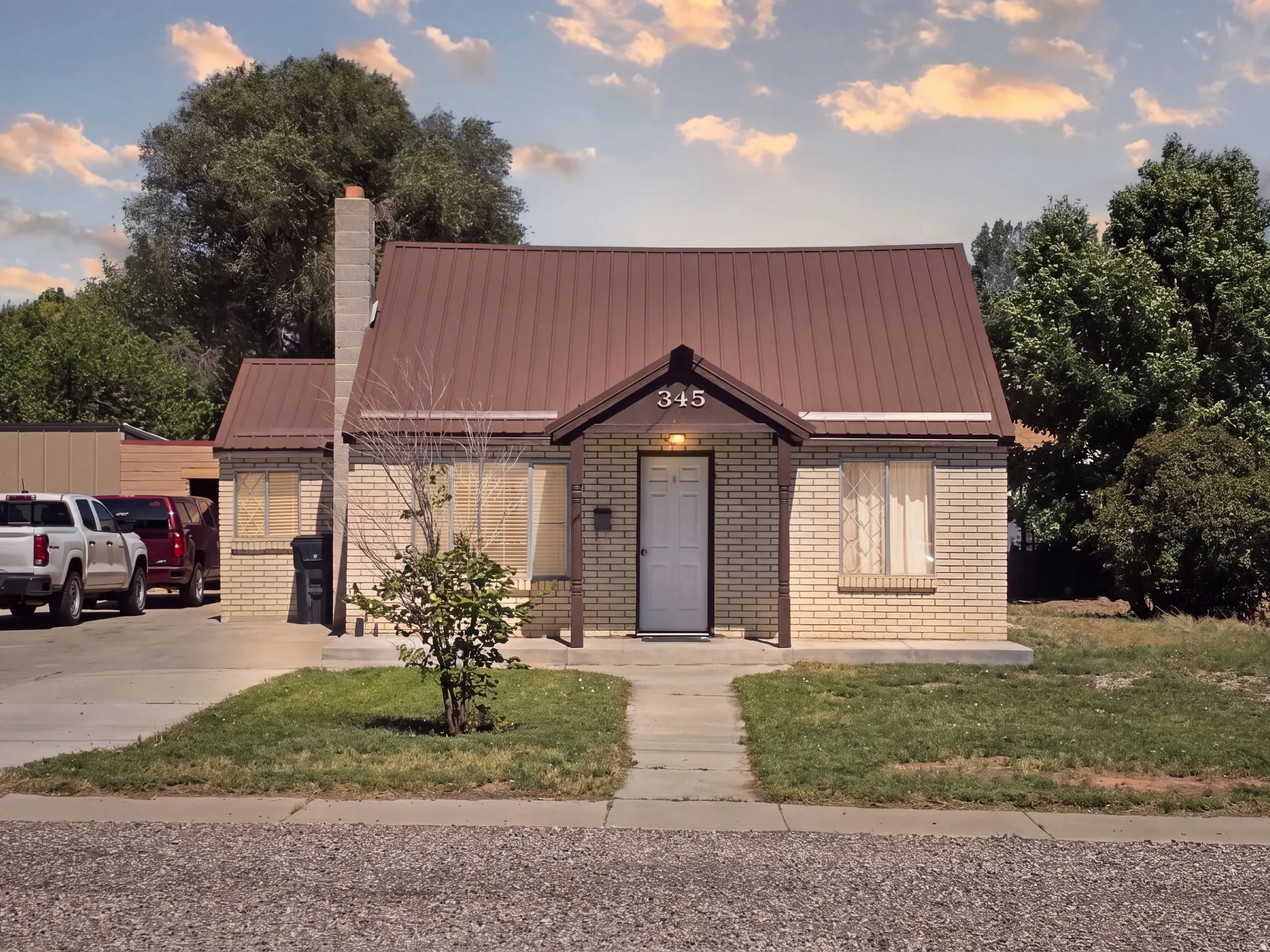 Brick exterior with a metal roof, front porch entry, and a concrete walkway