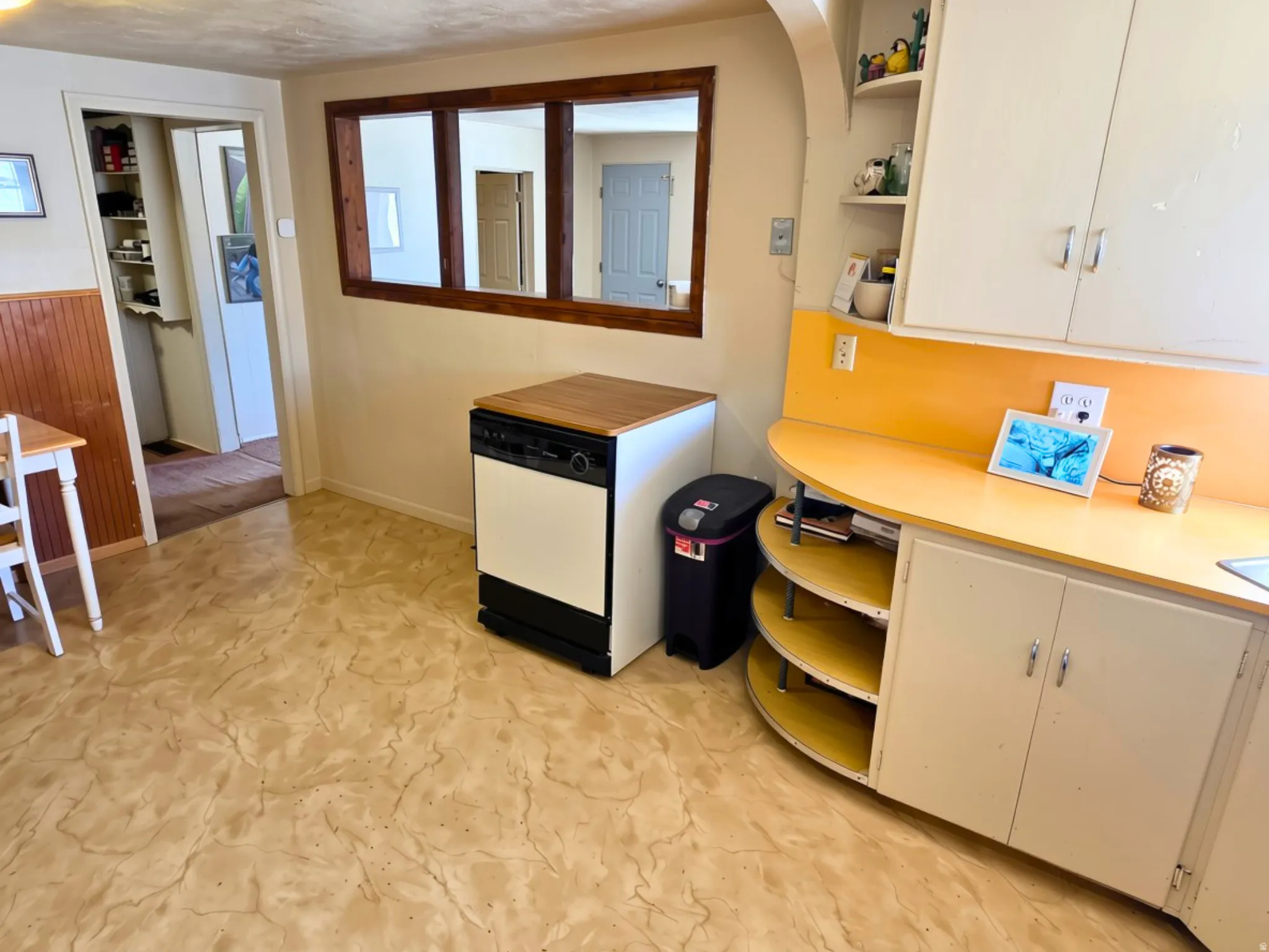 Built-in cabinetry with a curved countertop, integrated shelving, wood-paneled wall accent, and durable flooring
