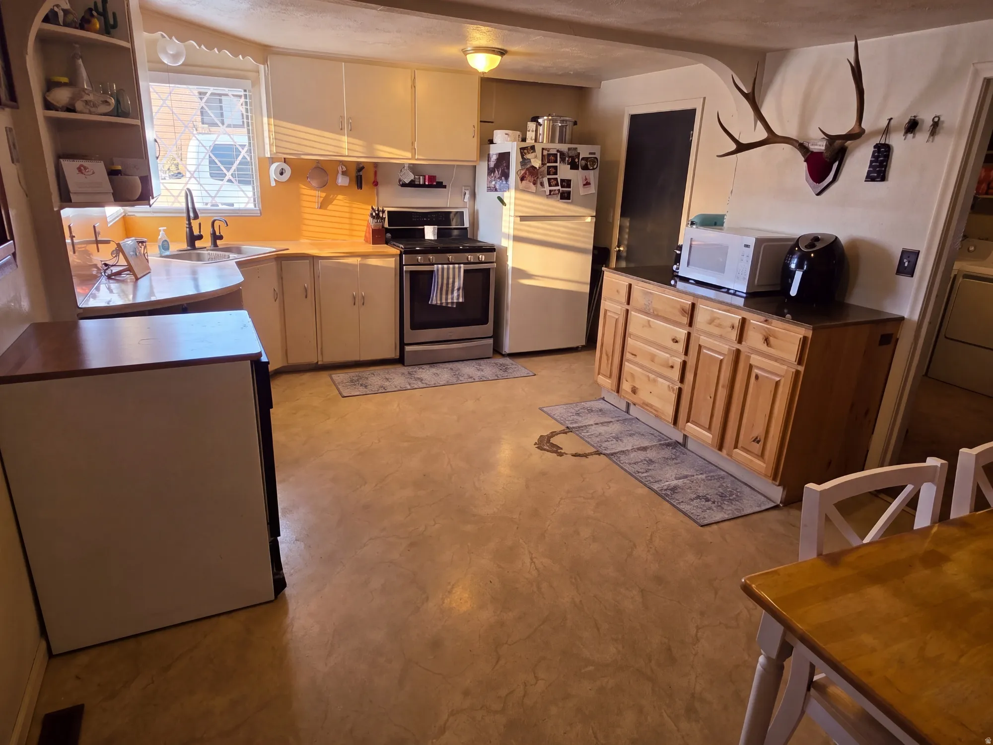U-shaped kitchen with white cabinetry, stainless steel range, and built-in shelving