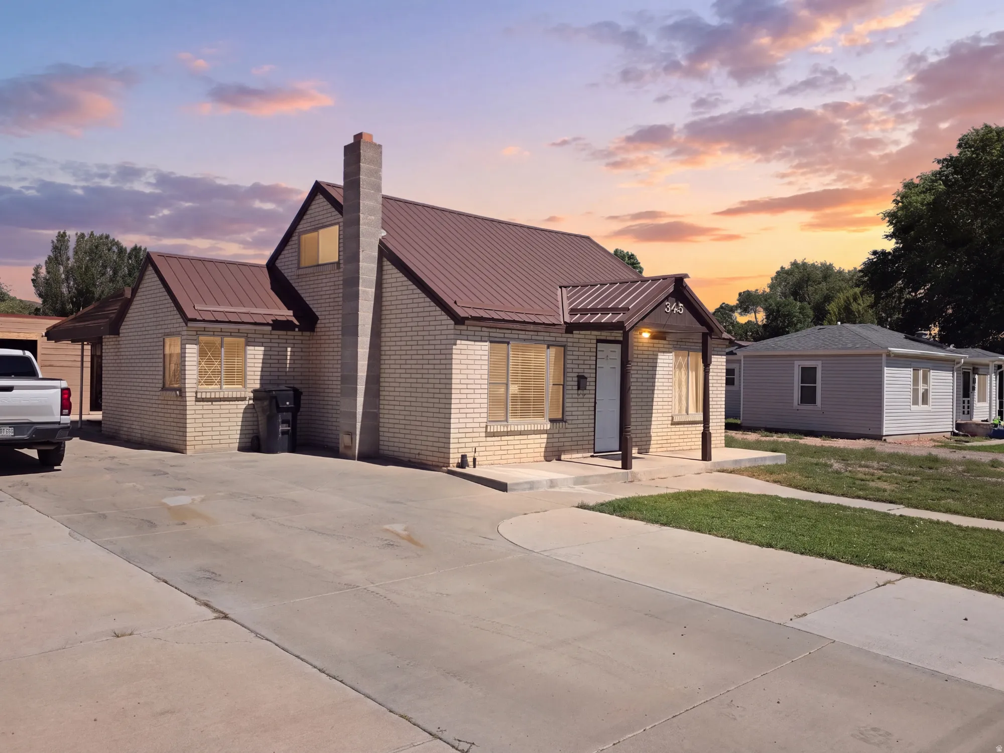 Brick exterior with a brown metal roof, covered front entry, and a concrete driveway