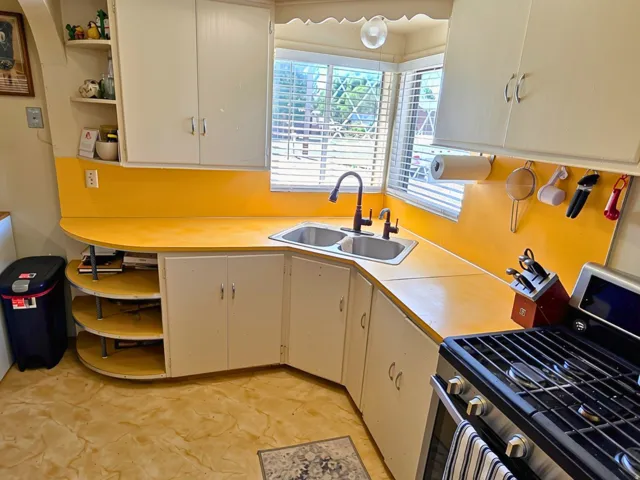 Corner kitchen sink with dual basins and a gooseneck faucet, set into a yellow countertop