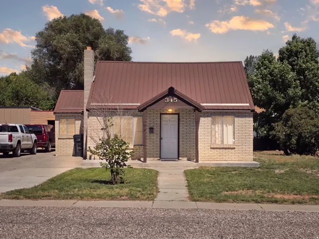 Brick exterior with a metal roof, front porch entry, and a concrete walkway
