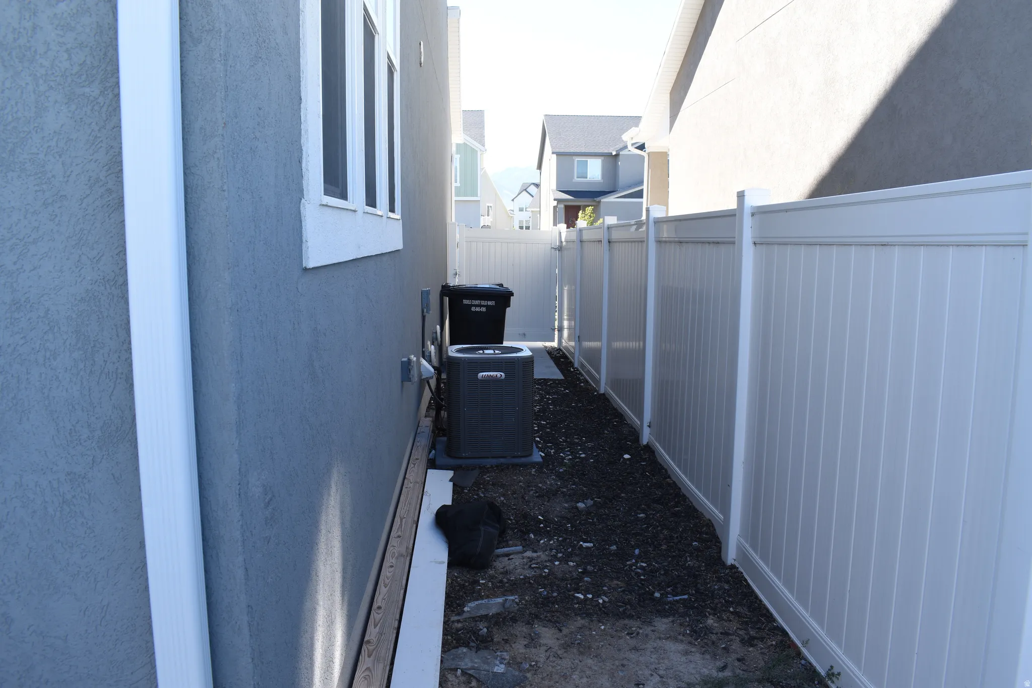 Stucco exterior with white-framed windows, white gutter system, and white privacy fencing