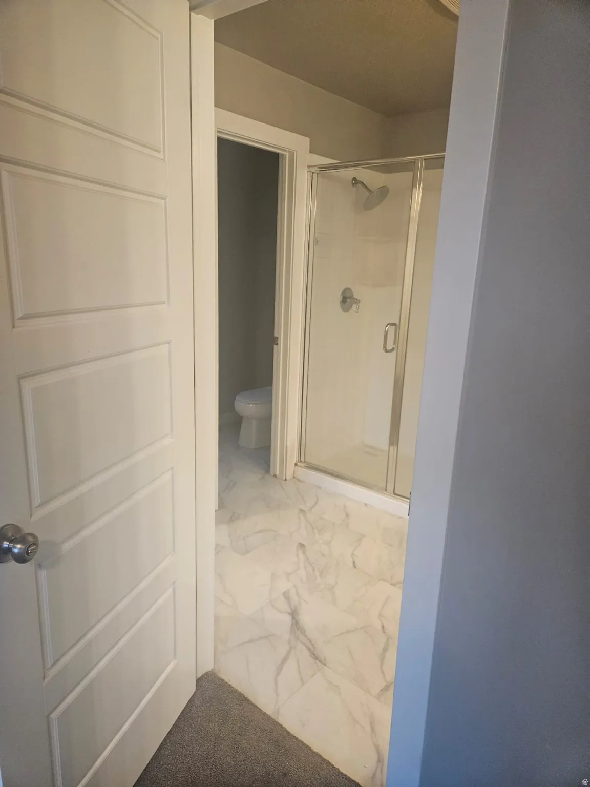 Bathroom featuring a glass-enclosed shower, white tile flooring, and a panel-style door