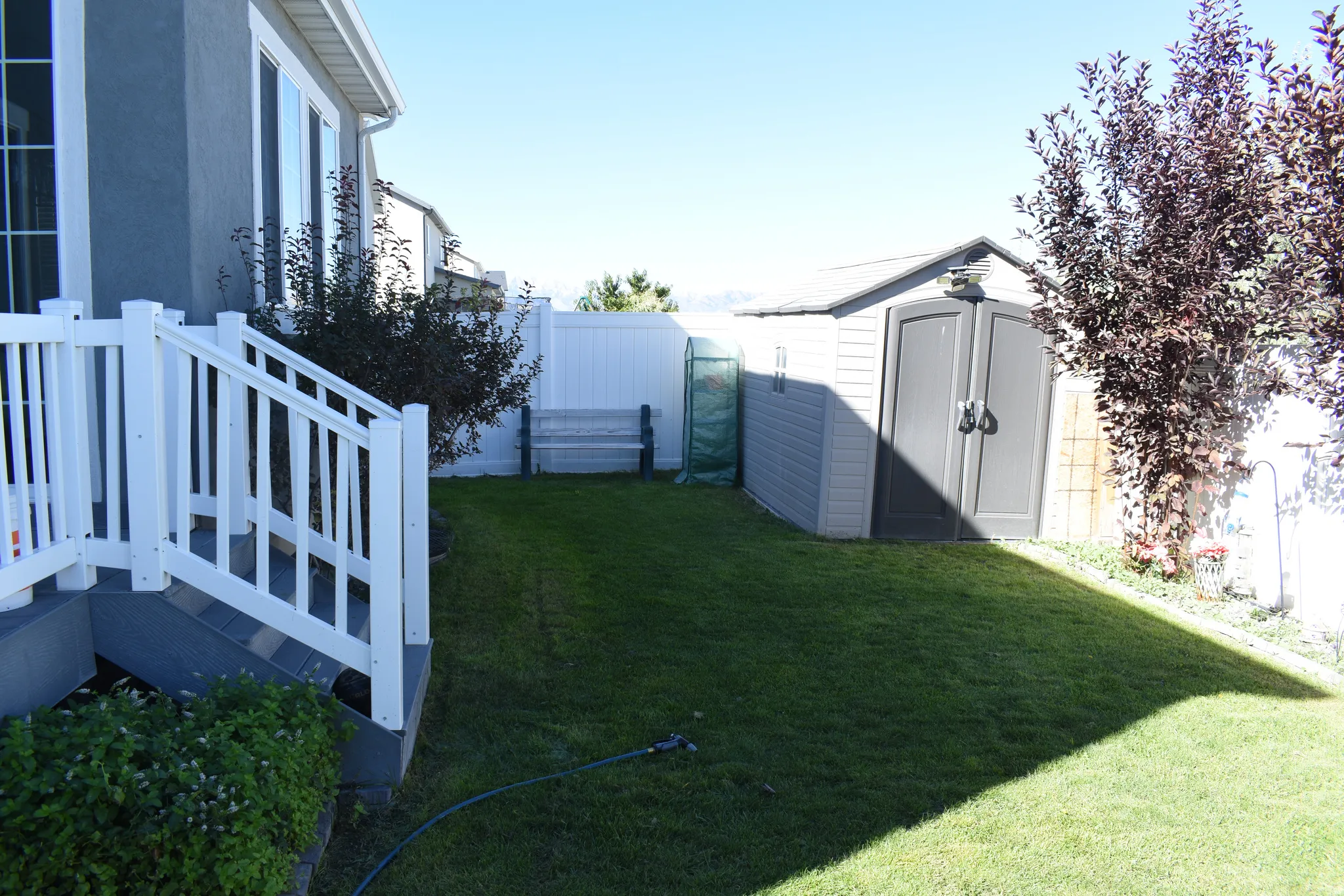 Expansive green lawn, white privacy fencing, and a built-in storage shed