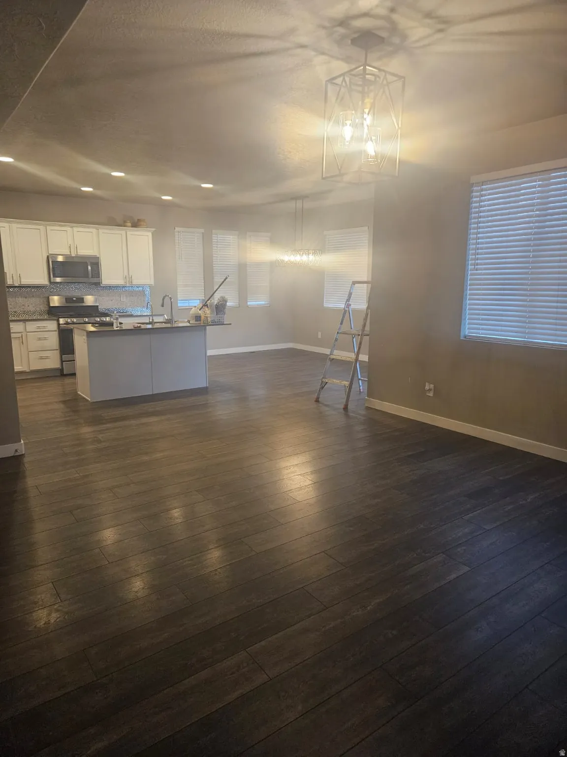 Open-concept living area with dark wood-finish flooring, recessed lighting, and a contemporary geometric chandelier