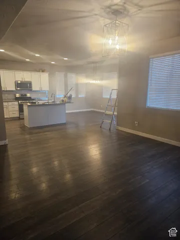 Open-concept living area with dark wood-finish flooring, recessed lighting, and a contemporary geometric chandelier
